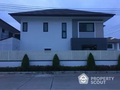 Modern two-story house with sleek design and fenced yard in suburban neighborhood.