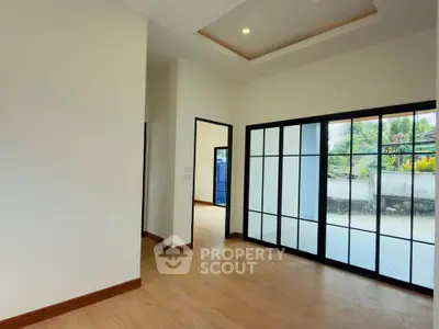 Spacious modern living room with large windows and wooden flooring, offering a bright and airy atmosphere.