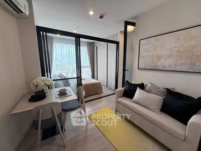 Modern apartment interior with cozy living room and bedroom separated by glass wall, featuring stylish decor.