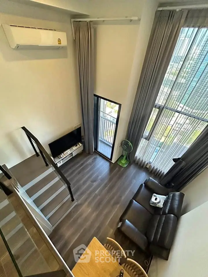 Modern loft-style living room with high ceilings and large windows offering a stunning view.