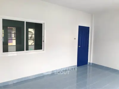 Spacious room with blue door and tiled floor, perfect for customization.