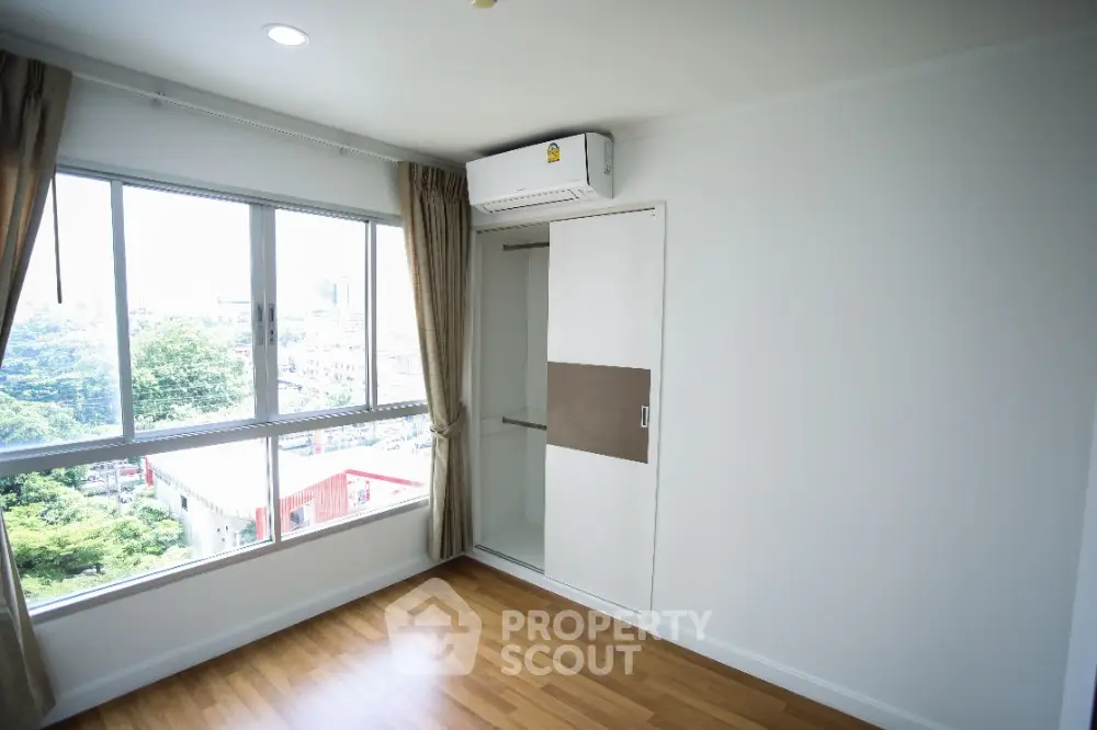 Bright bedroom with large window and built-in closet in modern apartment