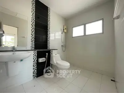Modern bathroom with sleek black and white tile design, featuring a shower and toilet.