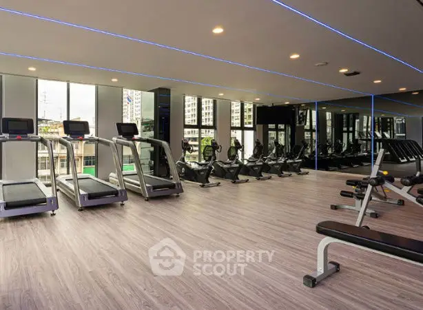 Modern gym with state-of-the-art equipment and large windows in a luxury building.