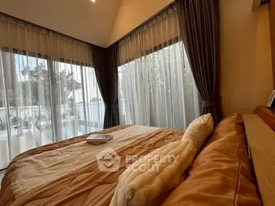 Luxurious bedroom with large windows and elegant curtains, offering a serene and cozy atmosphere.