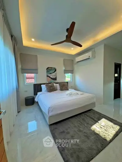 Luxurious bedroom with modern decor, ceiling fan, and natural light, perfect for relaxation.