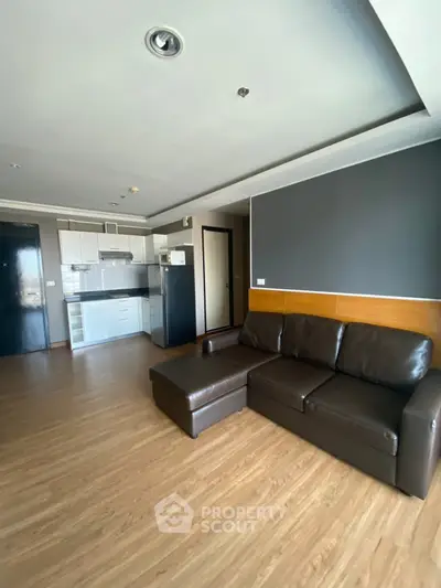 Modern living room with sleek leather sofa and open kitchen layout in stylish apartment.