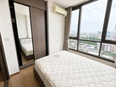 Modern bedroom with large windows offering stunning city views and ample natural light.