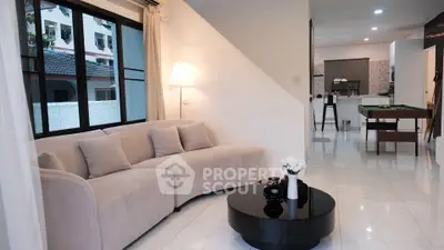 Modern living room with cozy beige sofa and sleek black coffee table, open layout to kitchen.