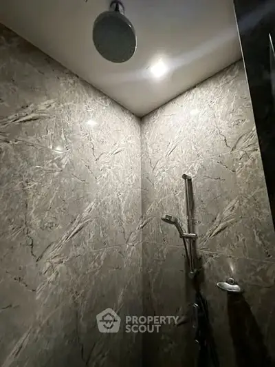 Luxurious marble-tiled shower with modern fixtures in a high-end bathroom.