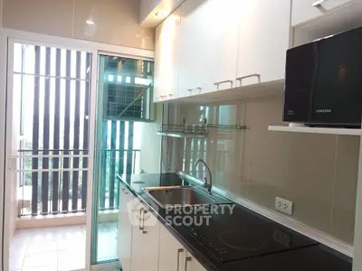 Modern kitchen with sleek cabinetry and balcony access in a contemporary apartment.