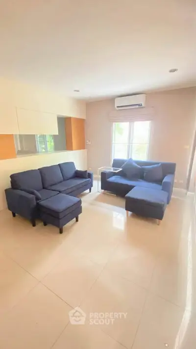 Spacious living room with modern blue sofas and large window for natural light.