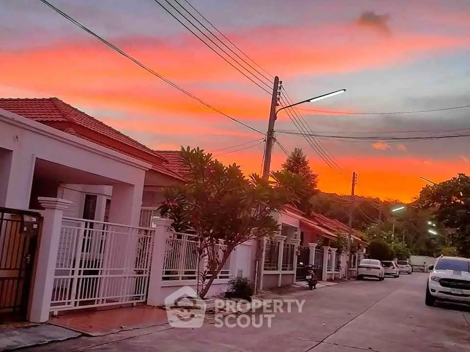 Charming suburban street with vibrant sunset sky and modern houses.