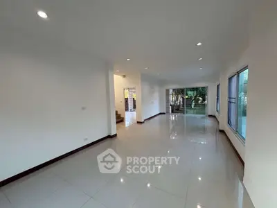 Spacious open-plan living room with large windows and garden view, perfect for family gatherings.