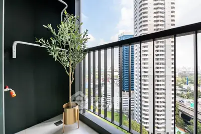 Modern balcony with stunning city view and potted plant, perfect for urban living.