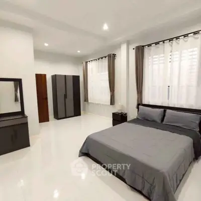 Spacious modern bedroom with sleek furniture and ample natural light.