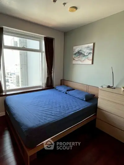 Modern bedroom with city view, featuring a cozy bed and stylish decor.