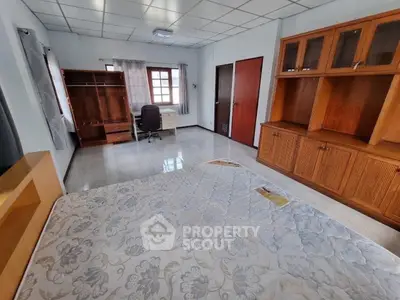Spacious bedroom with wooden furniture and large window for natural light.