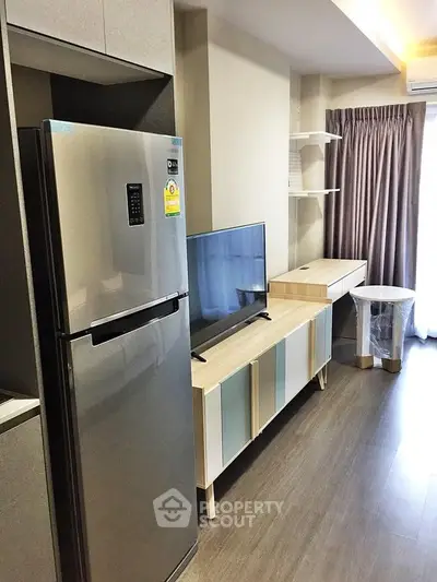 Modern living room with sleek fridge and stylish TV unit in a cozy apartment.