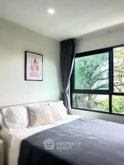 Cozy bedroom with large window and scenic view, featuring elegant decor and natural light.