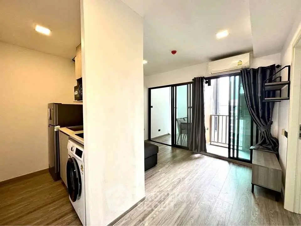 Modern apartment interior with open layout, featuring kitchen and living area leading to a balcony.