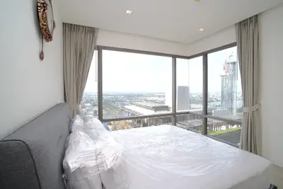 Luxurious bedroom with panoramic city view and modern decor in high-rise apartment.
