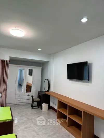 Spacious bedroom with modern furniture and wall-mounted TV