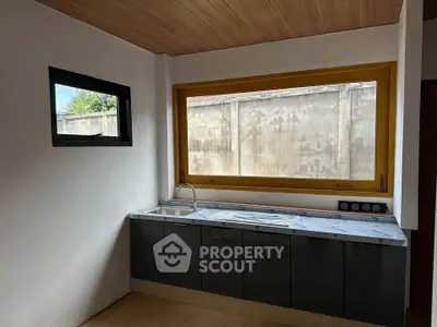 Modern kitchen with sleek black cabinets and large window for natural light.