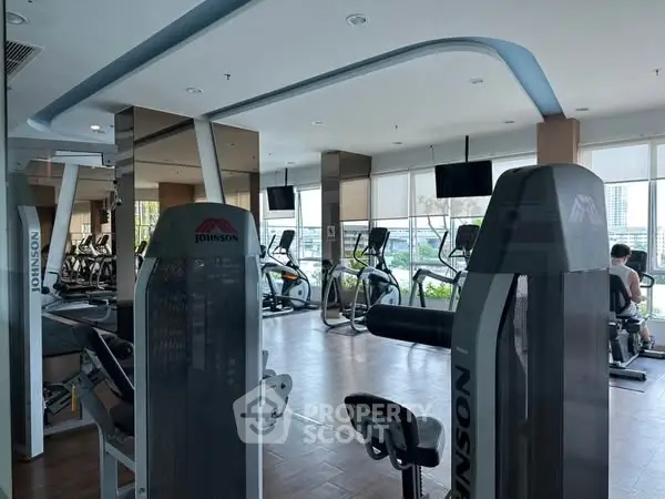 Modern gym with state-of-the-art equipment and large windows for natural light.