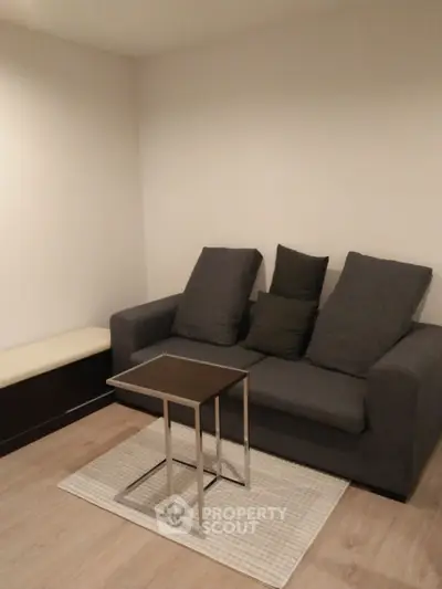 Cozy living room with modern gray sofa and sleek coffee table on wooden flooring.