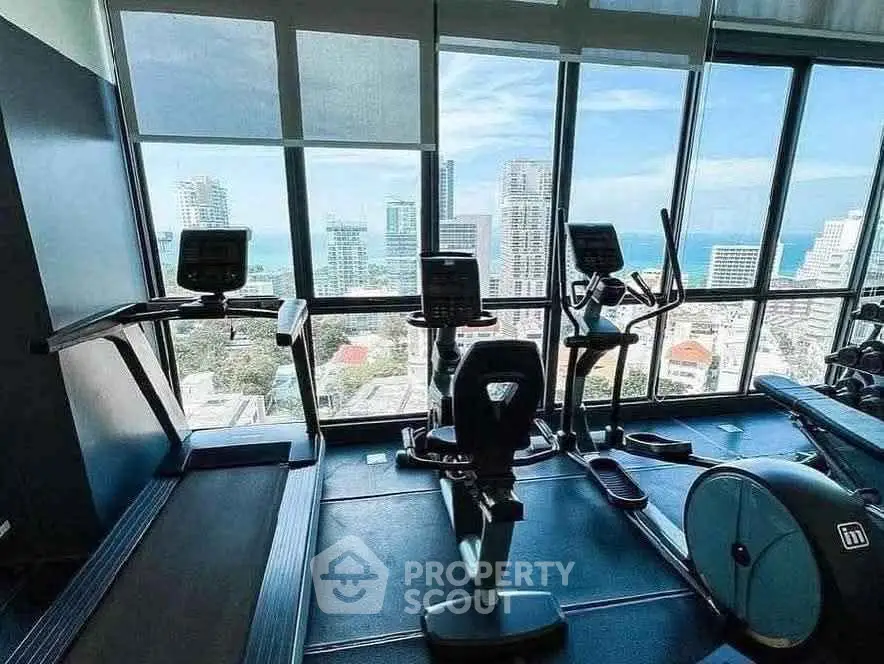 Modern gym with city view and state-of-the-art equipment in high-rise building.