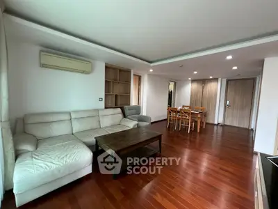 Spacious living room with wooden flooring and modern furniture in a stylish apartment.