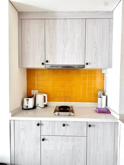 Charming compact kitchen with modern appliances and vibrant yellow backsplash, perfect for cozy urban living.