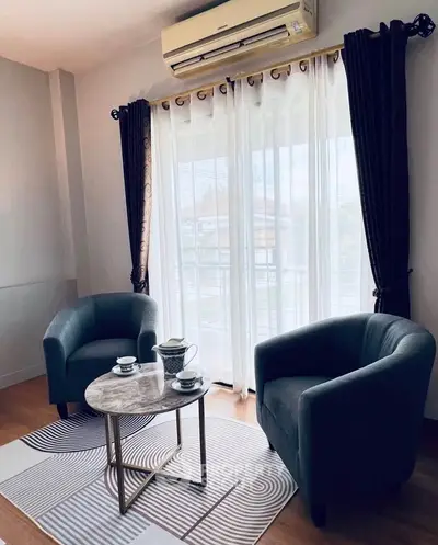 Cozy living room with elegant armchairs and a coffee table by large window.