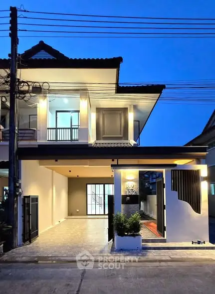 Modern two-story house with stylish exterior lighting and spacious driveway at dusk.