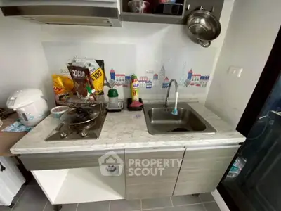 Compact kitchen with modern appliances and stylish backsplash in cozy apartment.