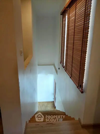 Elegant staircase with wooden blinds and natural light in modern home