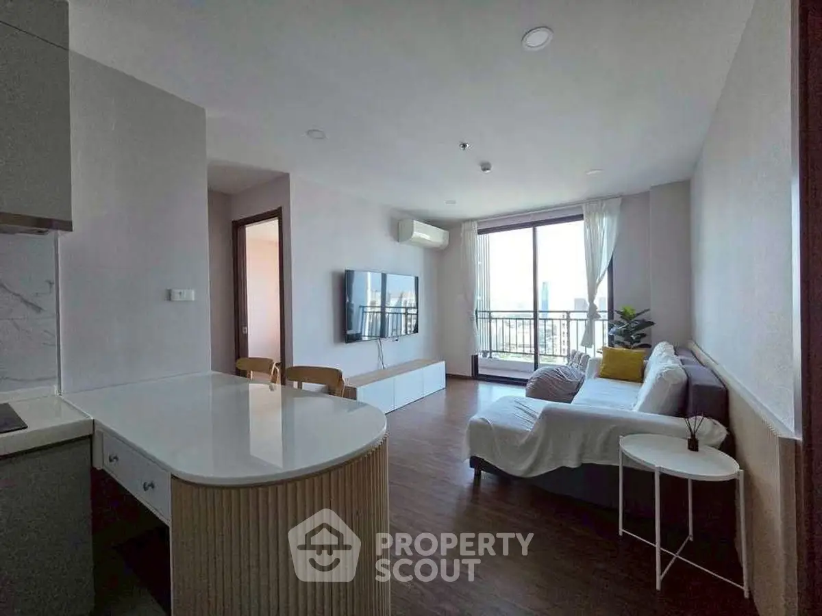 Modern living room with open kitchen and balcony view in a stylish apartment.