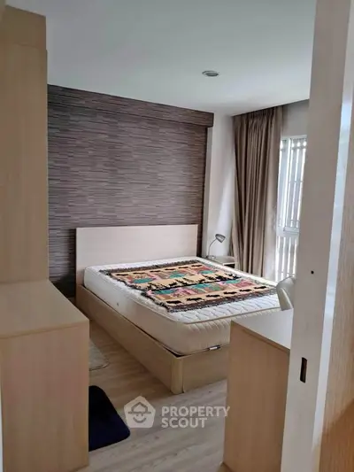 Cozy bedroom with modern decor and large window offering natural light.