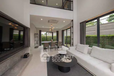 Spacious modern living room with high ceilings and large windows overlooking greenery.