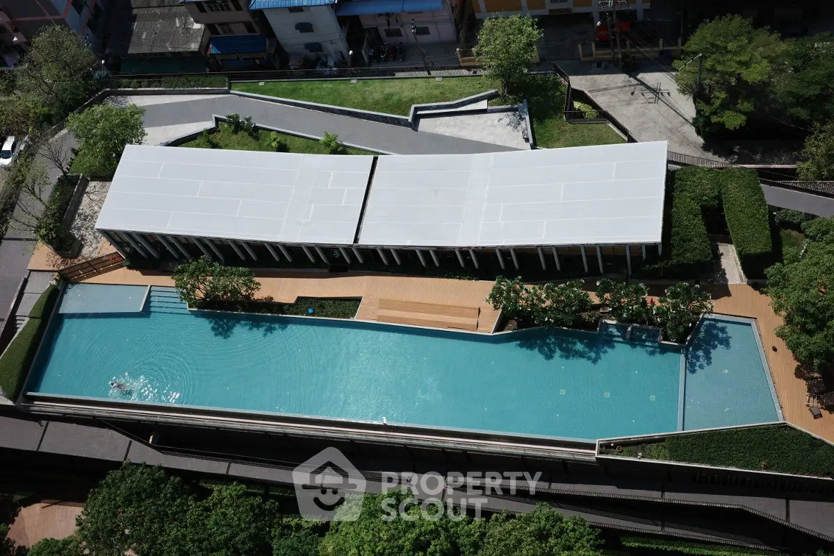 Stunning aerial view of modern residential complex with large swimming pool and lush greenery.