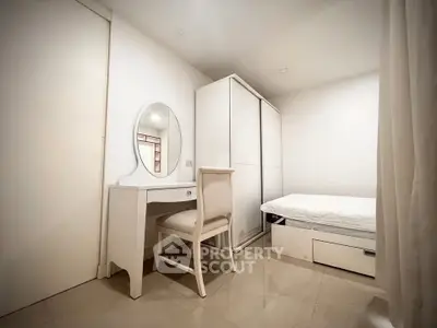 Cozy minimalist bedroom with sleek white furniture and ample storage space.