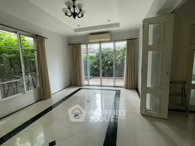 Spacious living room with large windows and garden view, perfect for natural light lovers.