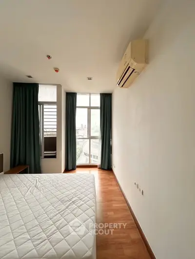 Spacious bedroom with large windows and air conditioning in modern apartment.