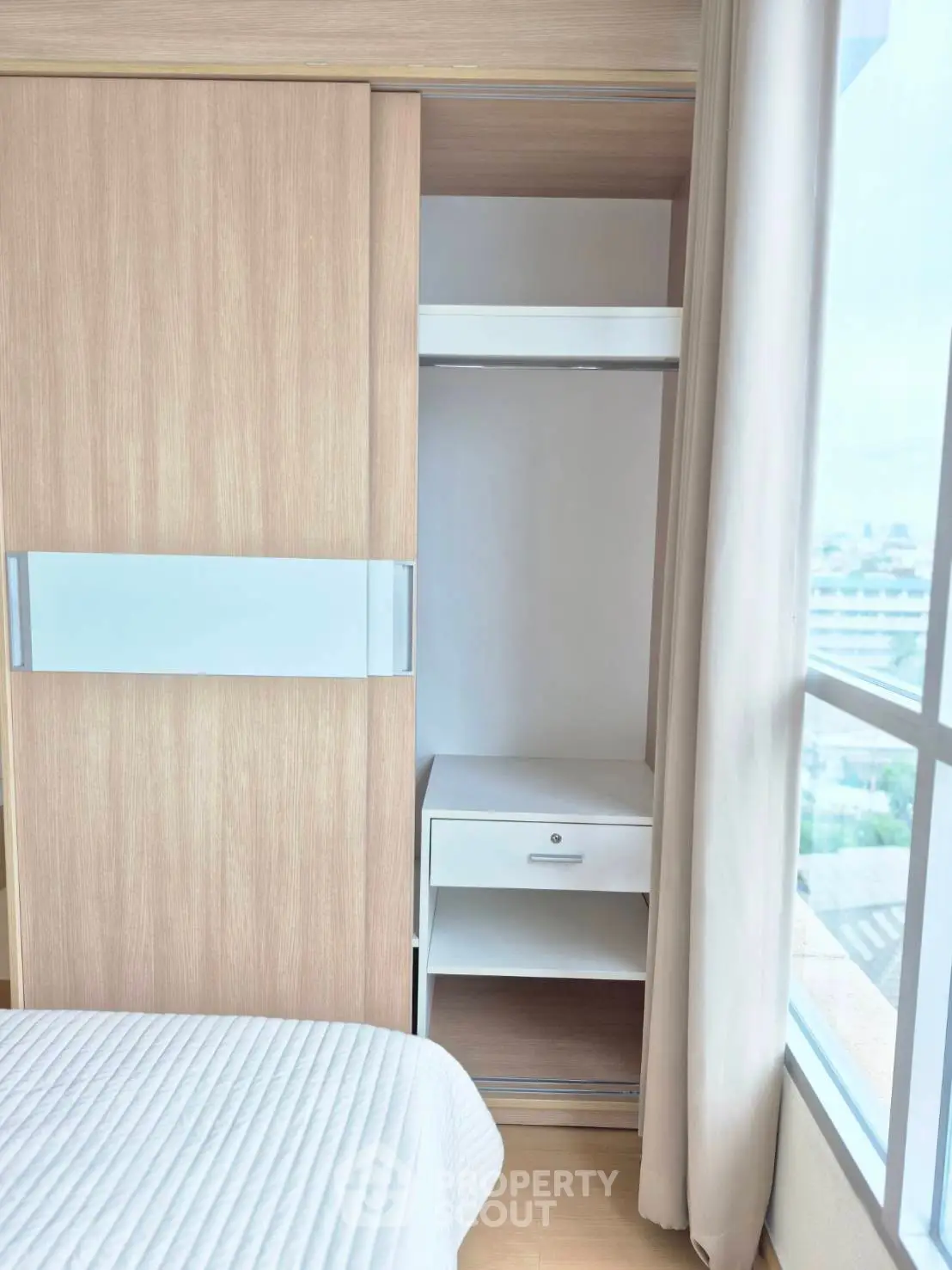 Modern bedroom with built-in wardrobe and large window offering natural light.