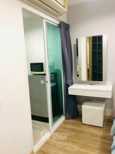 Cozy bedroom with sliding glass door leading to compact kitchen area, featuring modern appliances.