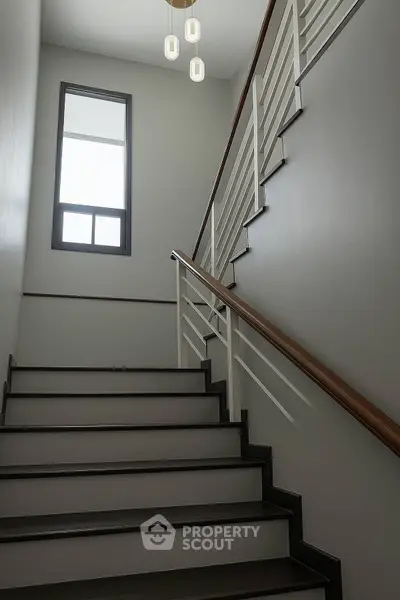 Elegant staircase with modern railing and pendant lighting in a stylish home interior.