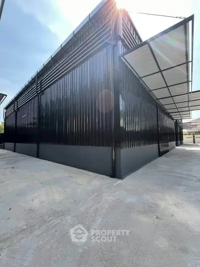 Modern industrial-style building with sleek black metal exterior and open canopy roof.