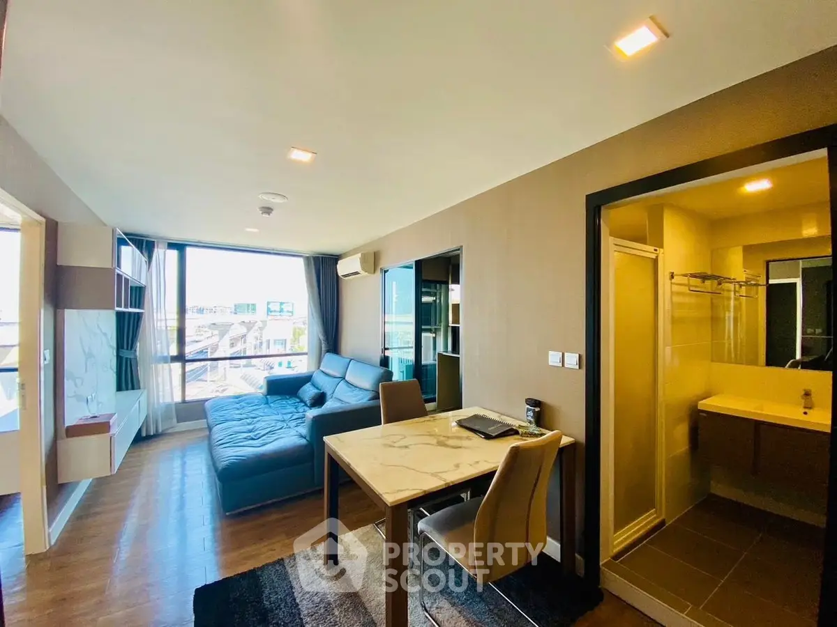 Modern living room with open layout and city view, featuring a cozy sofa and dining area.