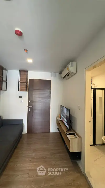 Modern living room with sleek wooden flooring and wall-mounted TV